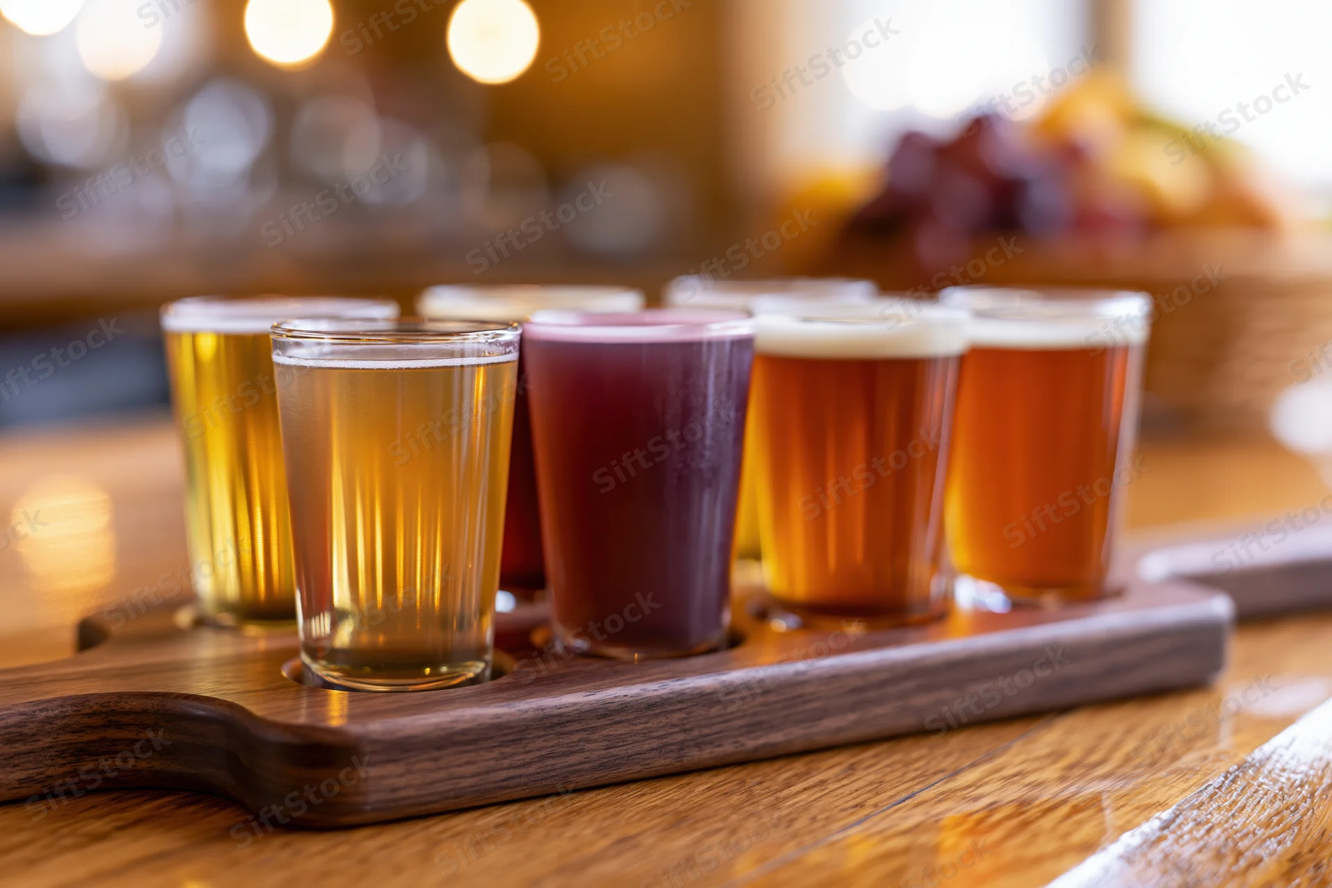 Six small glasses of craft beer arranged on a wooden tray on a bar counter