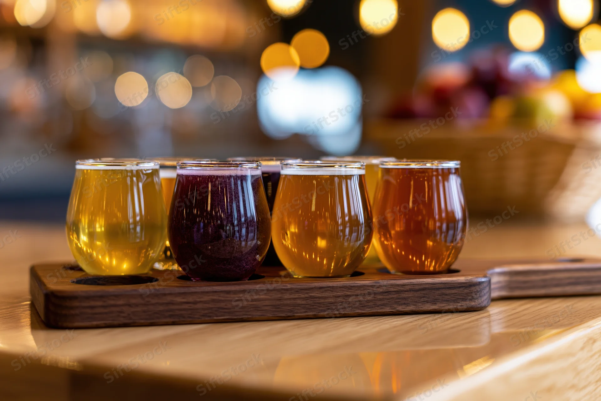 Six small glasses of craft beer arranged on a wooden tray at a bar