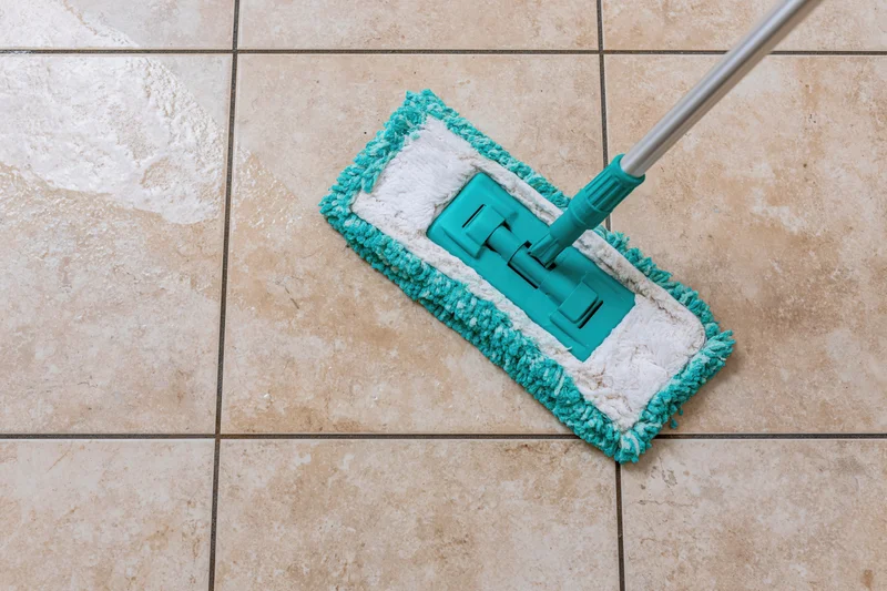 Teal microfiber flat mop cleaning a tiled floor leaving a clean path behind