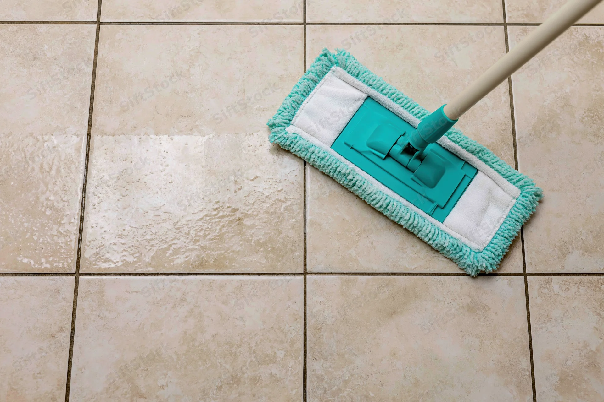 Teal microfiber flat mop cleaning a tiled floor leaving a wet streak behind