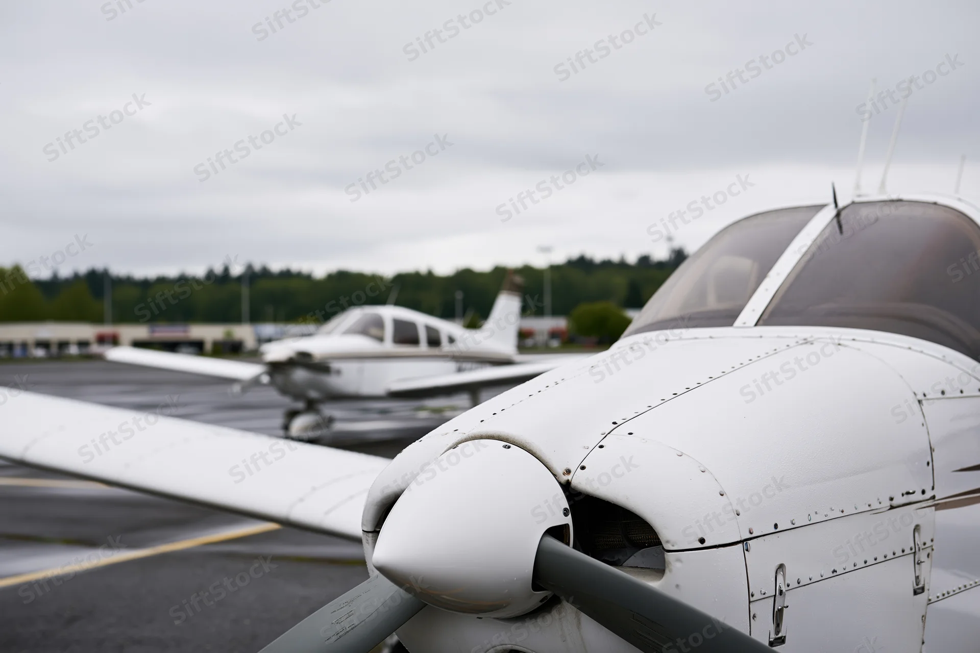 Two small single-engine propeller planes parked in a row on an airport tarmac