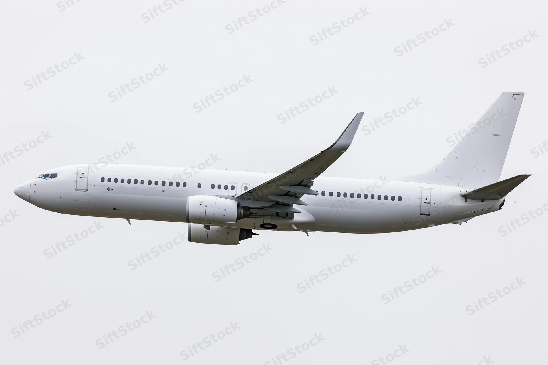 White unpainted commercial passenger jet in level flight side view against plain sky