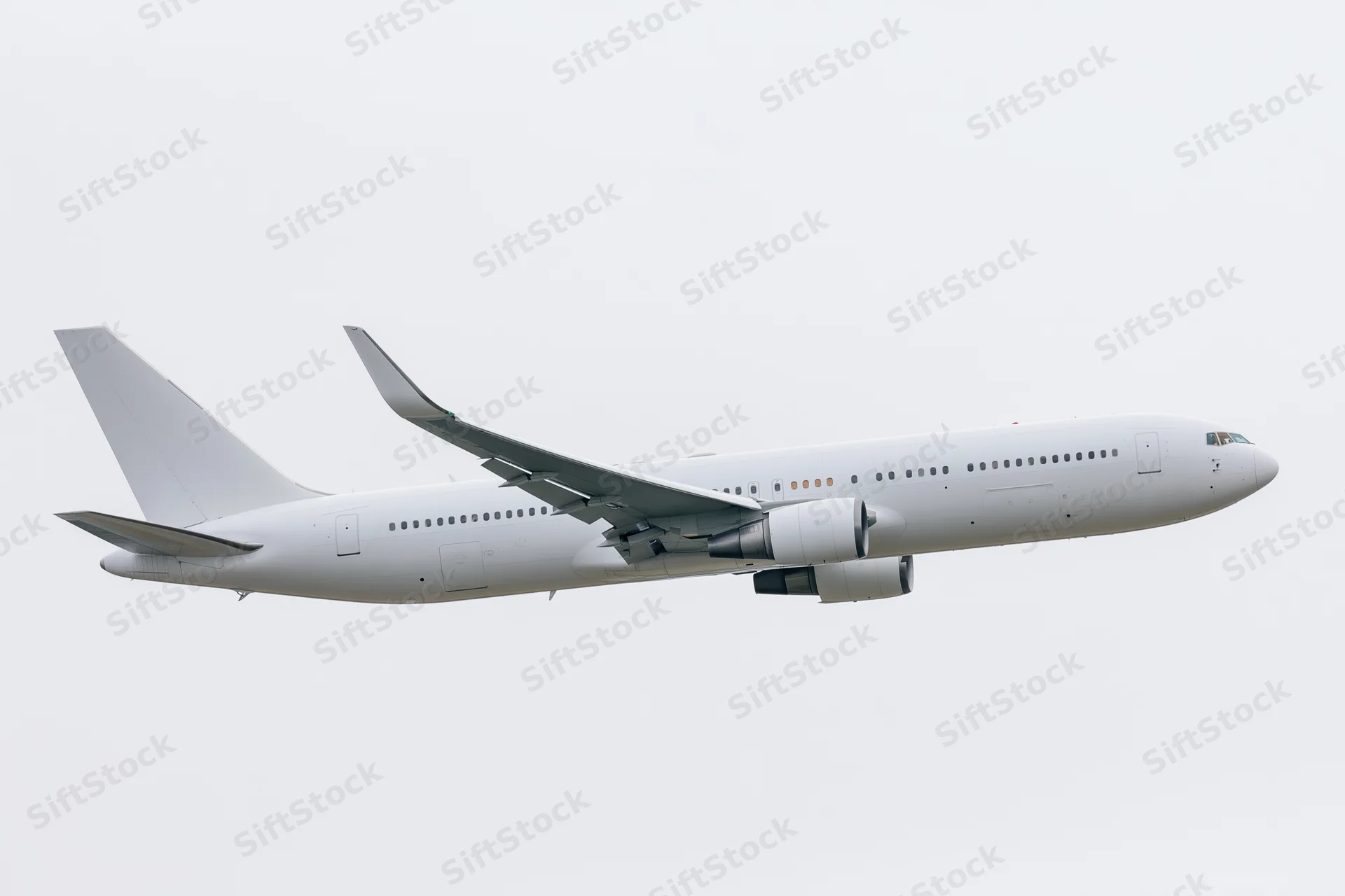 White unpainted commercial passenger jet in level flight side view against overcast sky