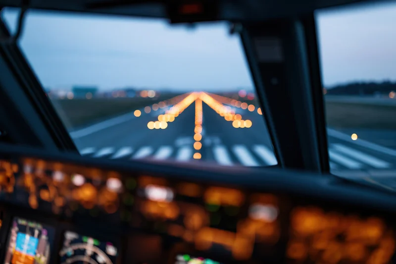 View from commercial aircraft cockpit during runway approach at dusk