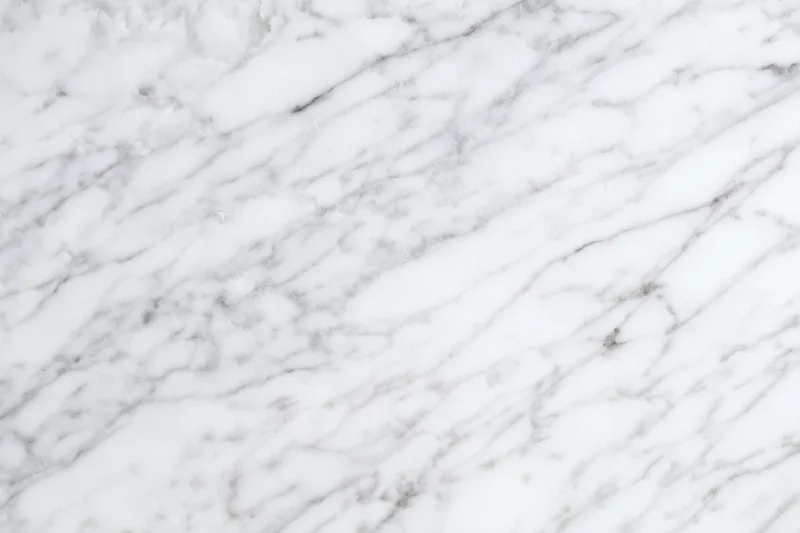 White marble surface with gray veining filling the frame as a seamless background