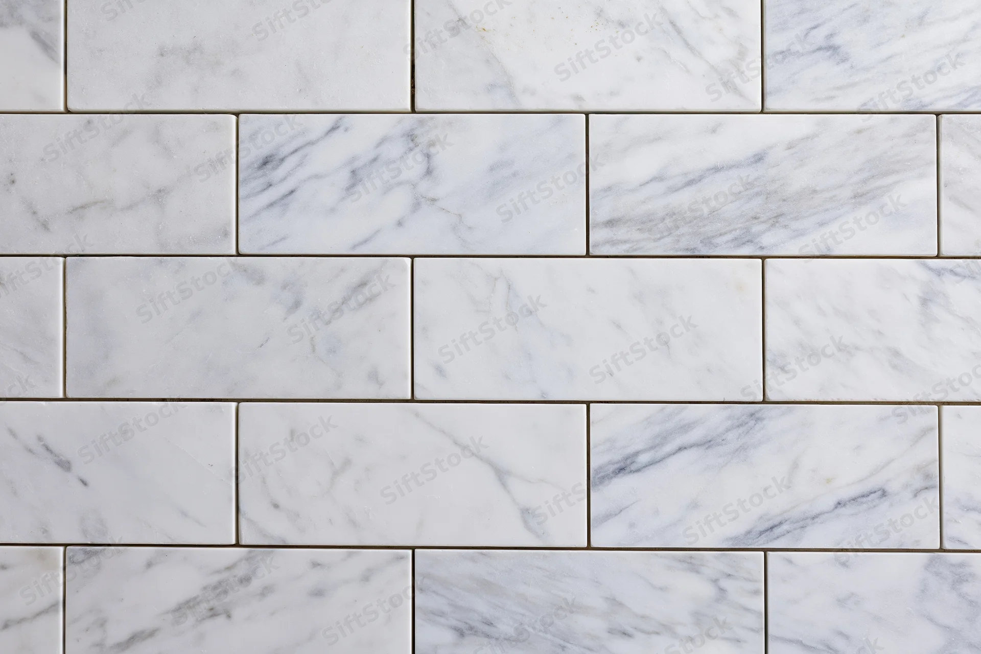 White marble tile wall surface filling the frame with rectangular tiles arranged in a staggered pattern