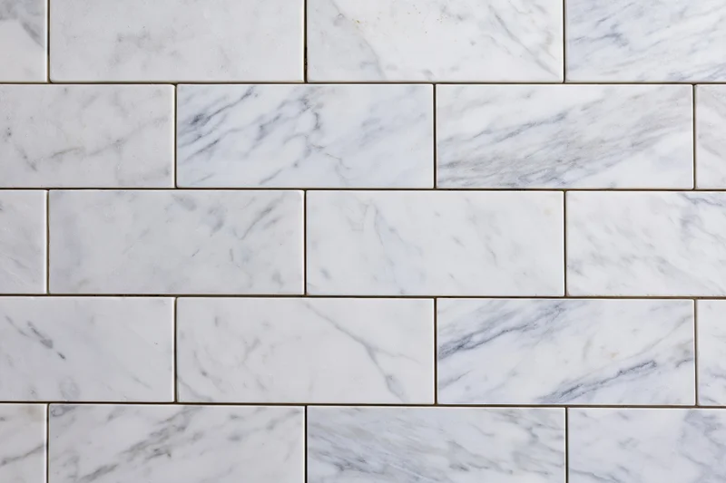 White marble tile wall surface filling the frame with rectangular tiles arranged in a staggered pattern