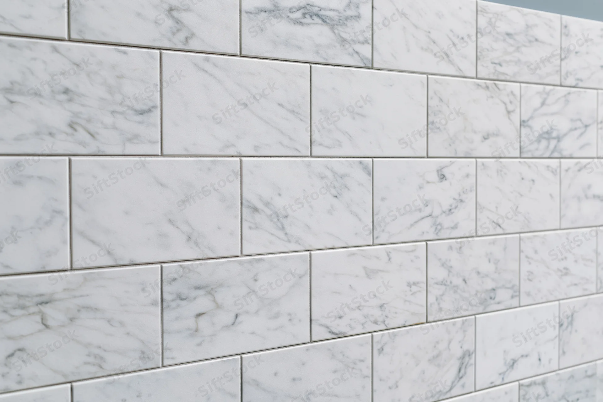 White marble tile wall surface filling the frame with grout lines in a staggered pattern