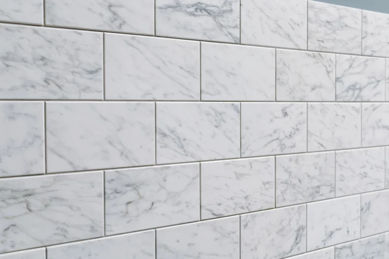 White marble tile wall surface filling the frame with grout lines in a staggered pattern