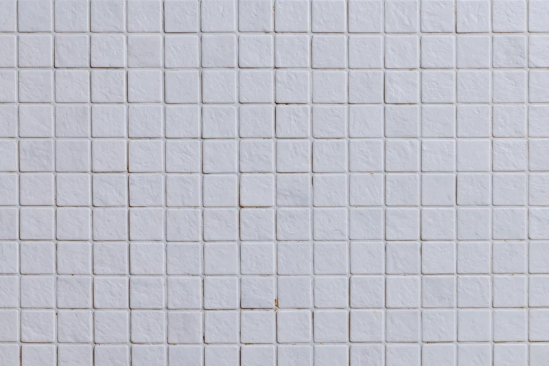 White small square mosaic tiles arranged in a grid pattern covering a wall surface