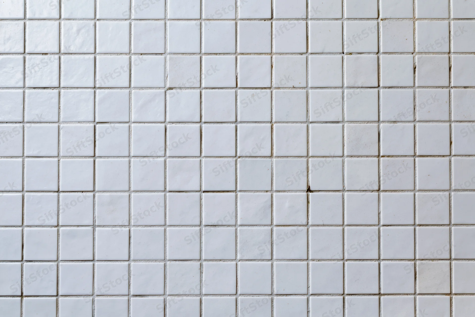 White square mosaic tile wall surface filling the frame with visible grout lines and minor discoloration