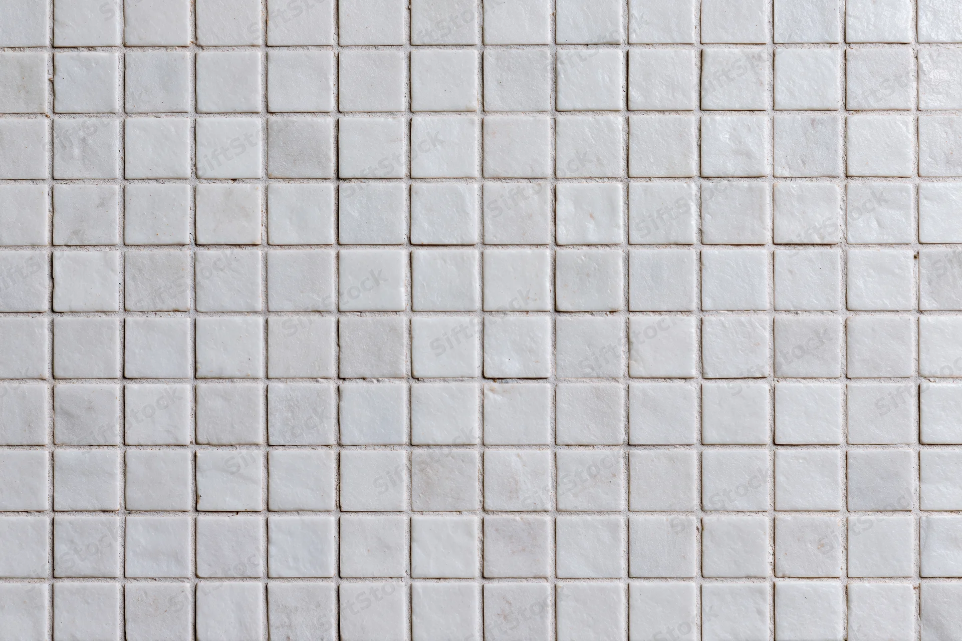 White square mosaic tiles arranged in a grid pattern covering a wall surface