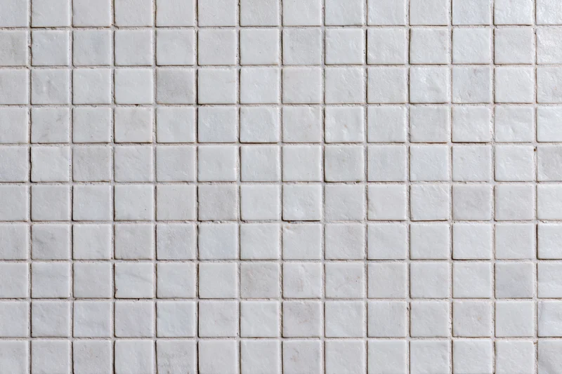 White square mosaic tiles arranged in a grid pattern covering a wall surface