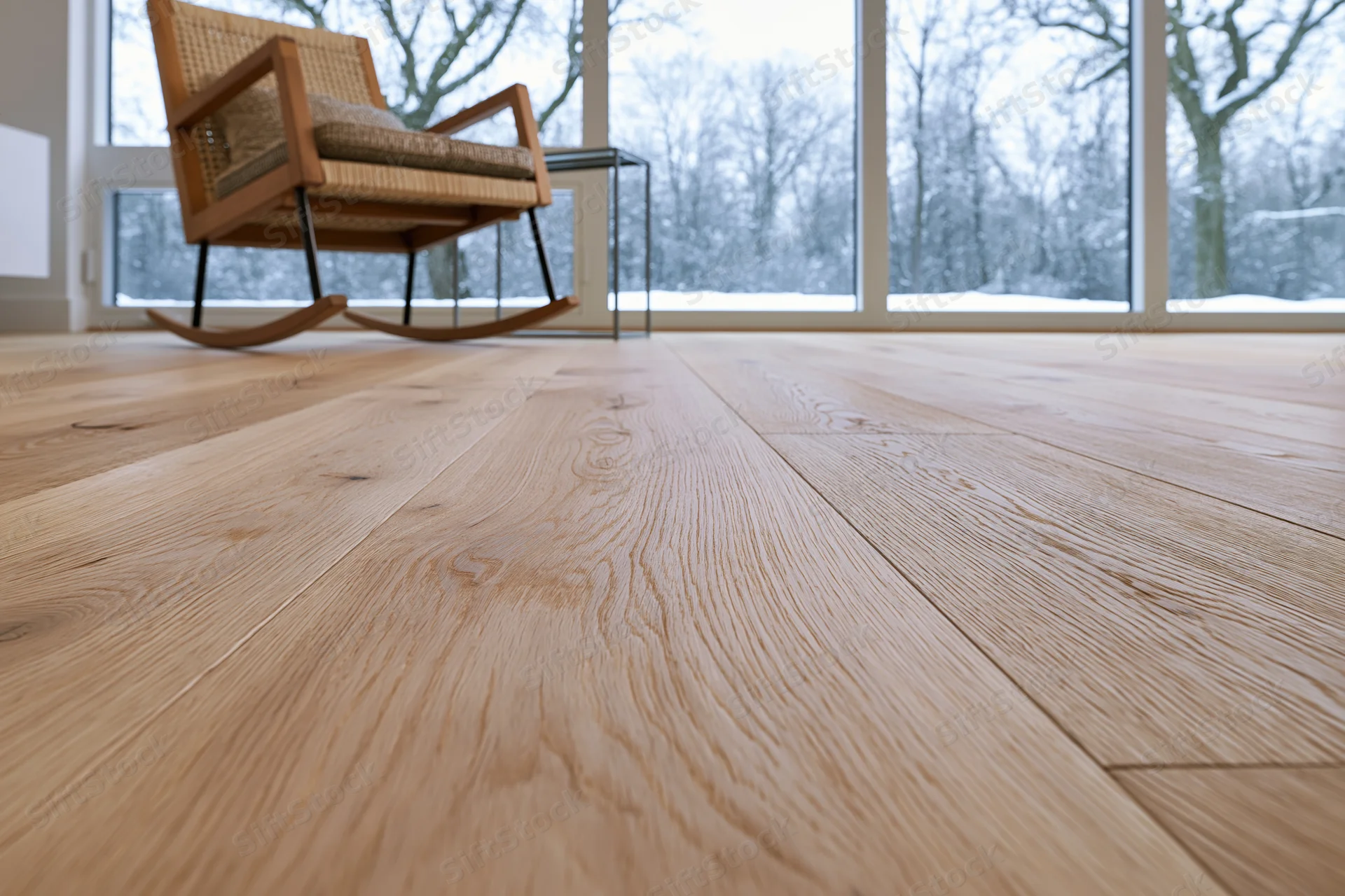 Wide-plank oak hardwood floor filling foreground with rocking chair and snowy view through large windows in modern living room