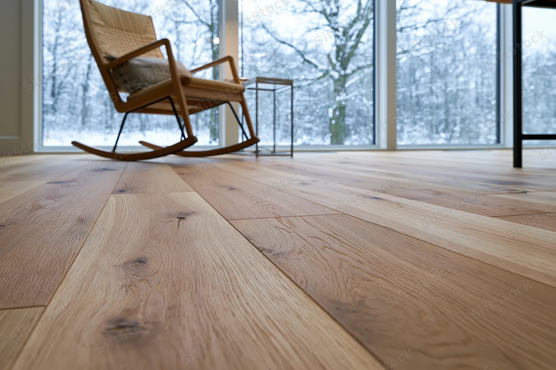 Wide-plank oak hardwood floor filling foreground with rocking chair and snowy forest view through large windows in modern living room