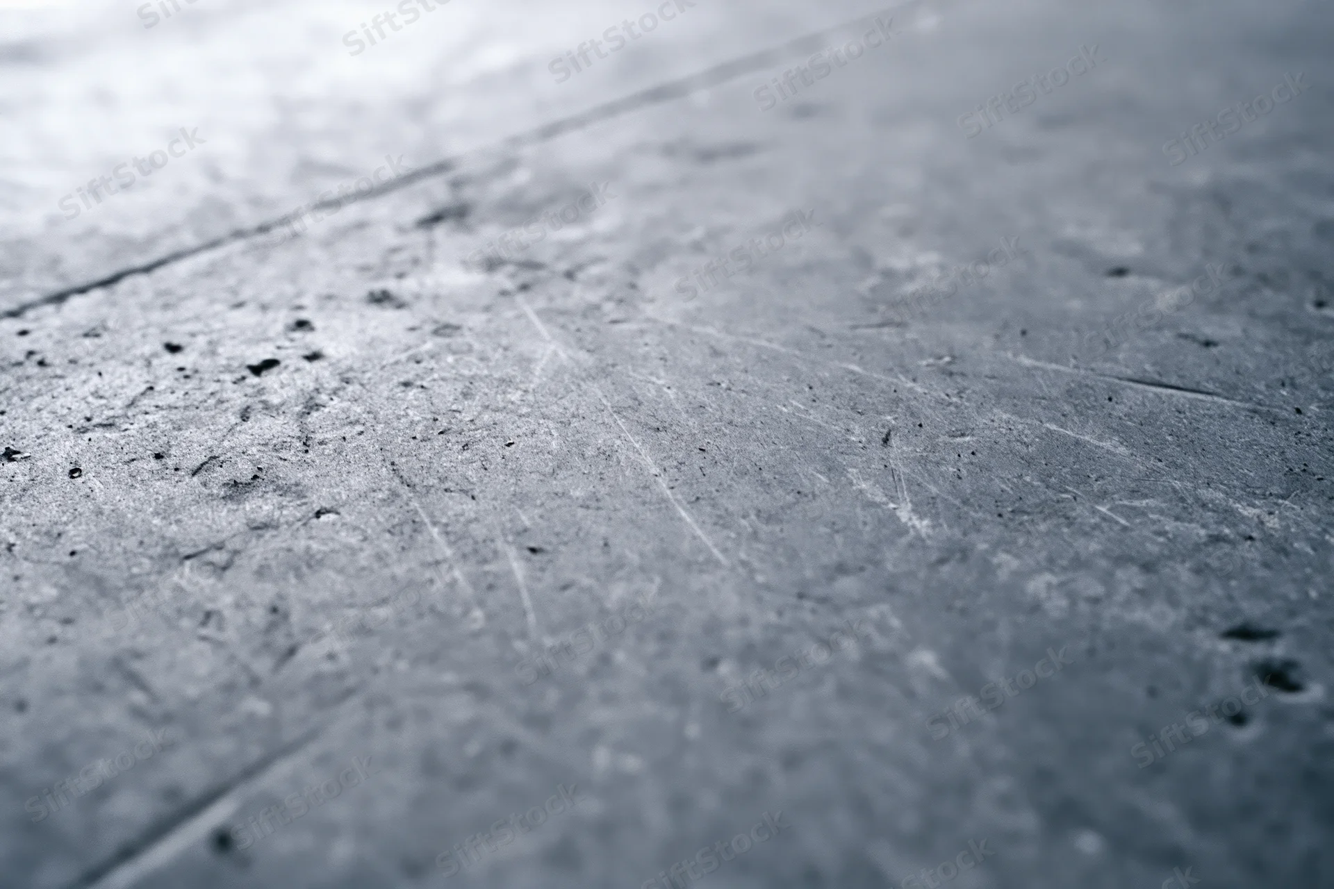 Worn concrete floor surface viewed diagonally with visible scratches and debris