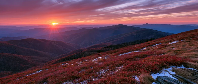 Panoramic view of autumn mountains at sunset with forested ridges and colorful foliage