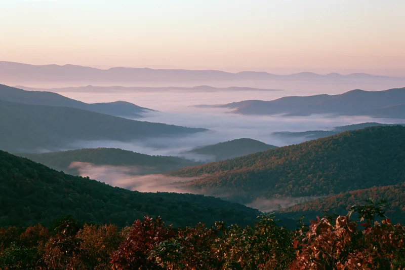 Mountain valley filled with low-lying fog at sunrise in autumn