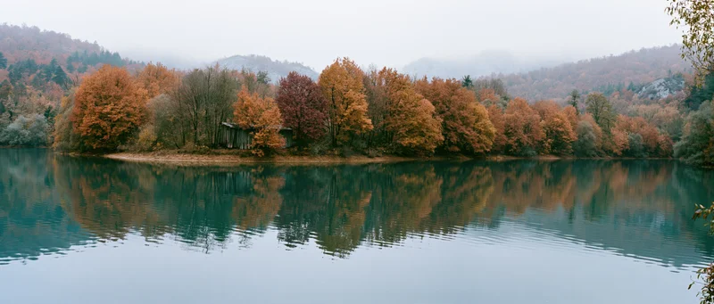 Calm mountain lake reflecting autumn trees along the shore