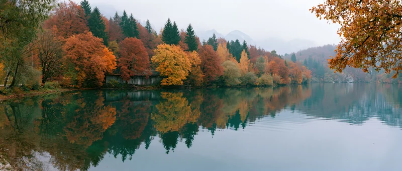 Calm mountain lake reflecting autumn foliage in still water