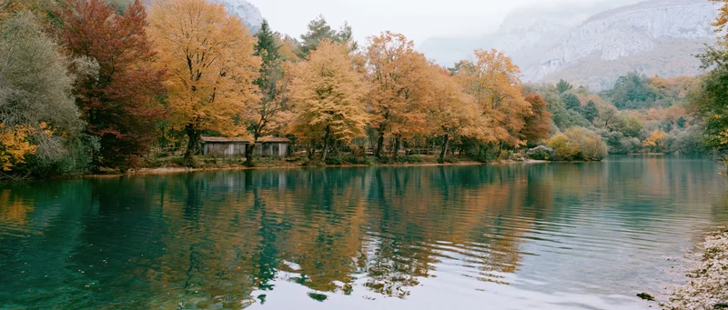 Calm mountain lake reflecting autumn trees along the shore
