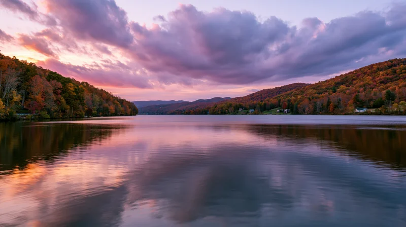 Calm mountain lake reflecting autumn forest hillsides at sunset