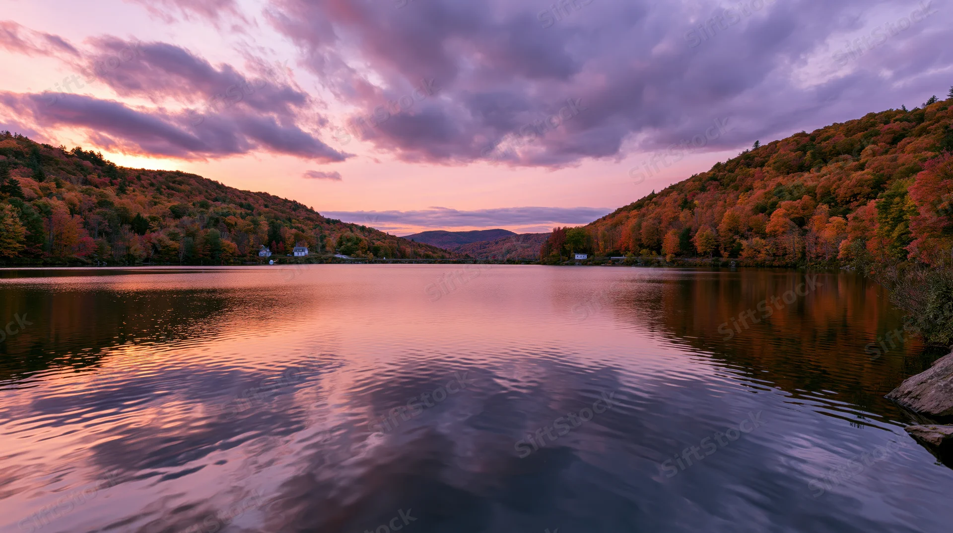Calm mountain lake reflecting autumn forest hillsides at sunset