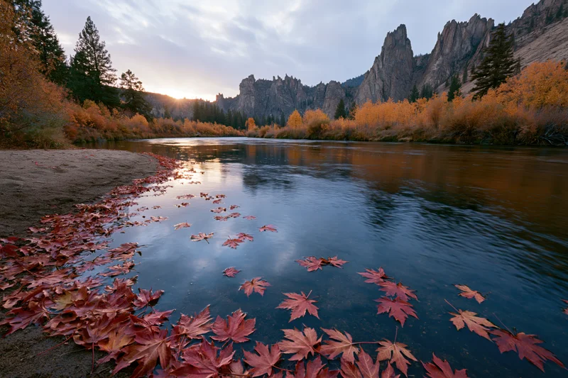 Calm river reflecting sunset light among autumn trees and mountains