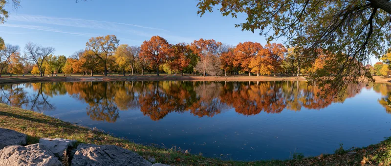 Calm pond reflecting autumn trees in a park setting