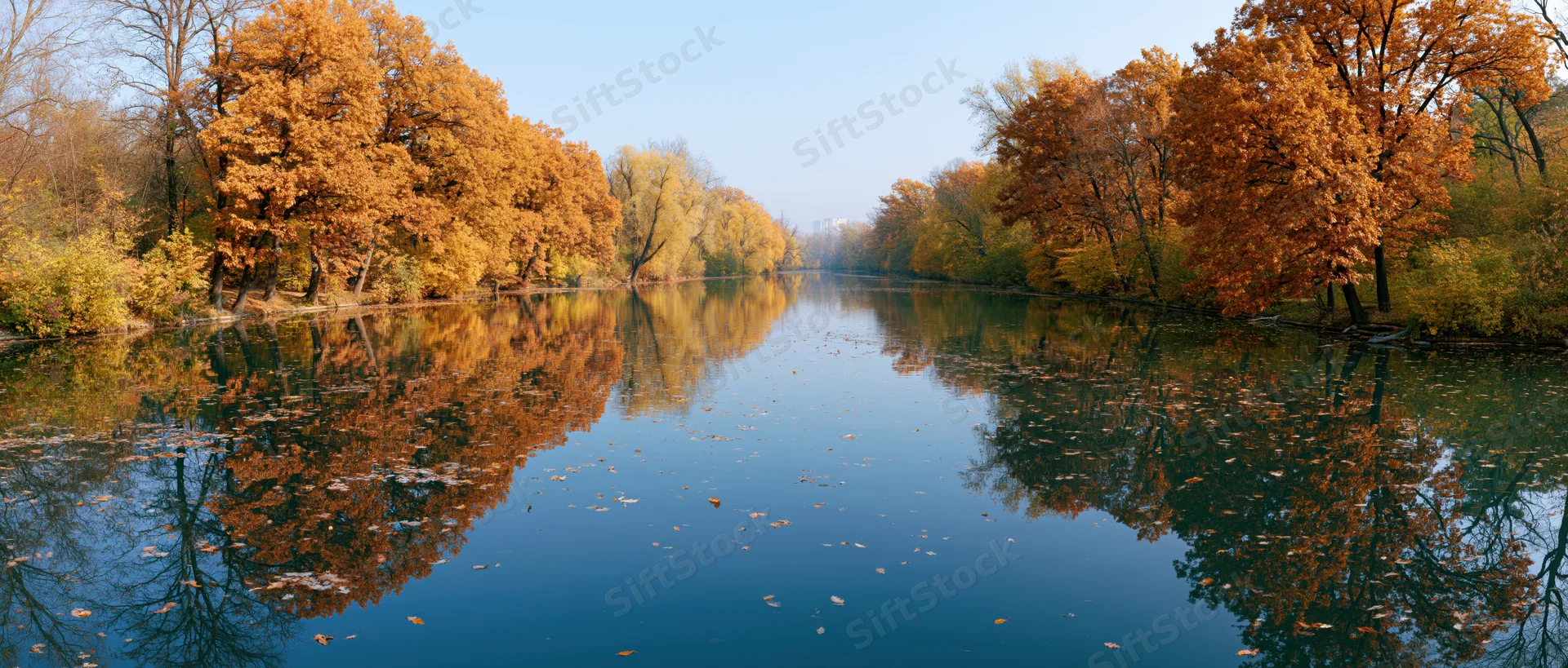 Calm river reflecting autumn trees in a park setting