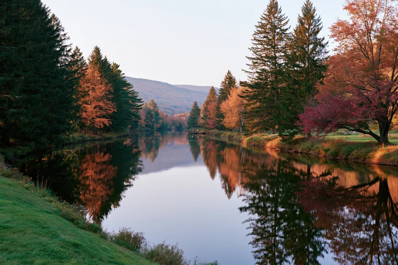 Calm river winding through autumn forest with colorful trees reflected in still water