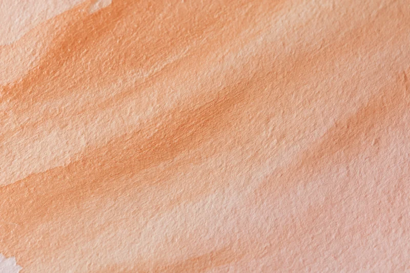 Watercolor paint texture on paper with soft peach and orange gradients