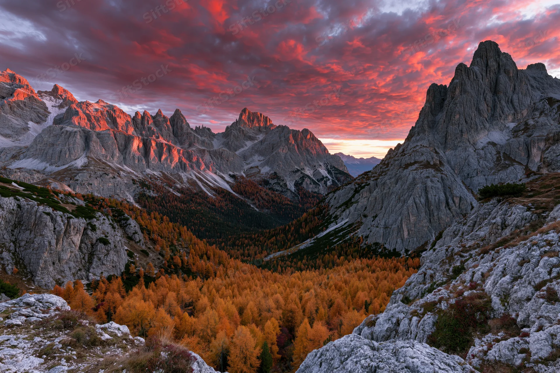 Massive limestone peaks of the dolomites at sunset with autumn forest in the valley