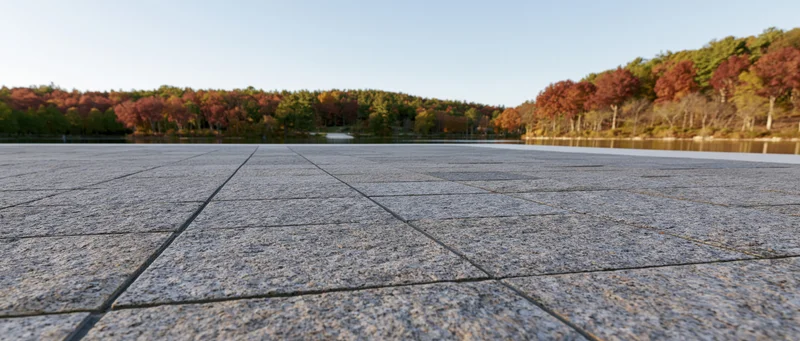 Granite-tiled plaza stretching toward a still lake bordered by autumn trees