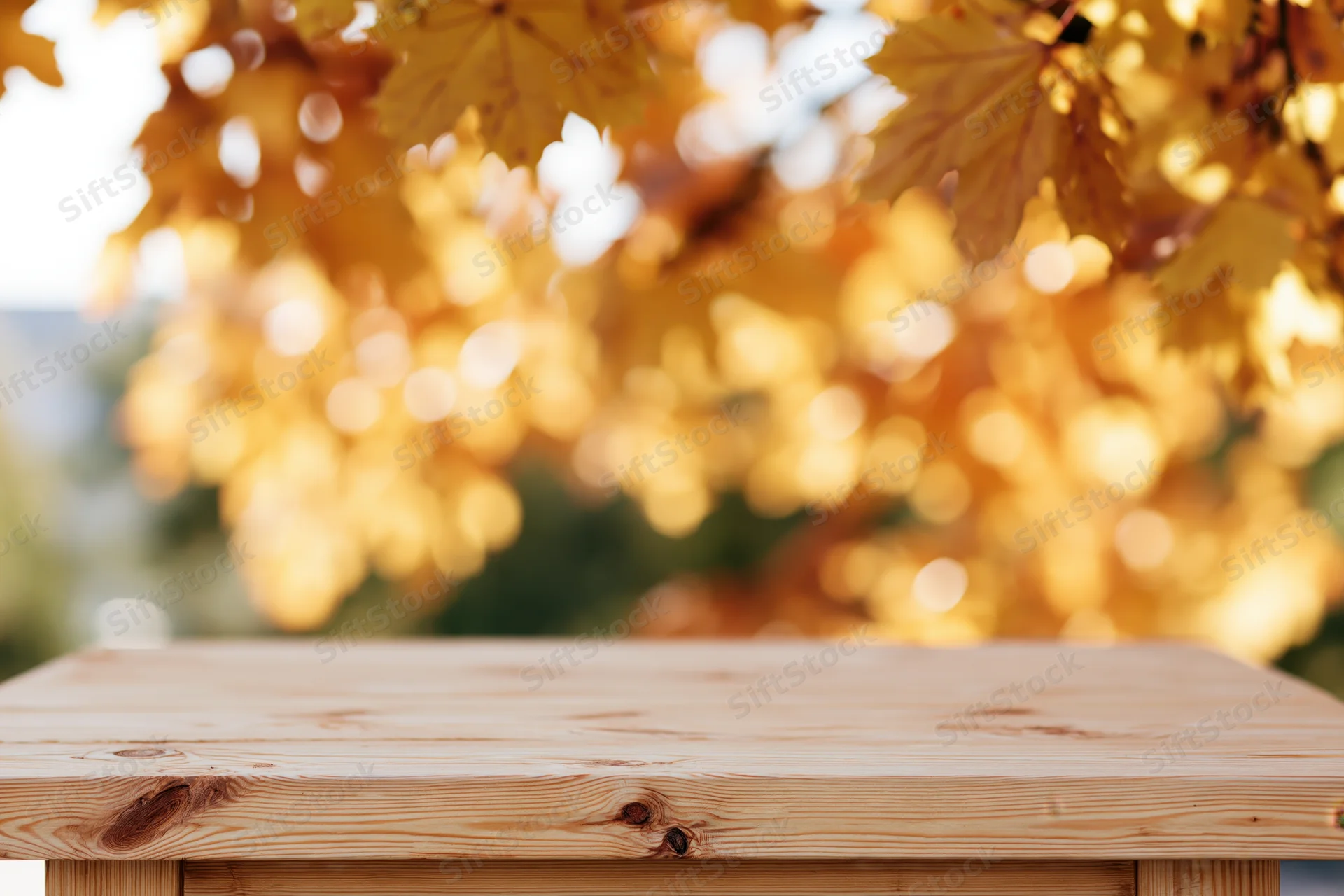 Light pine wooden table surface outdoors with autumn foliage in soft focus background