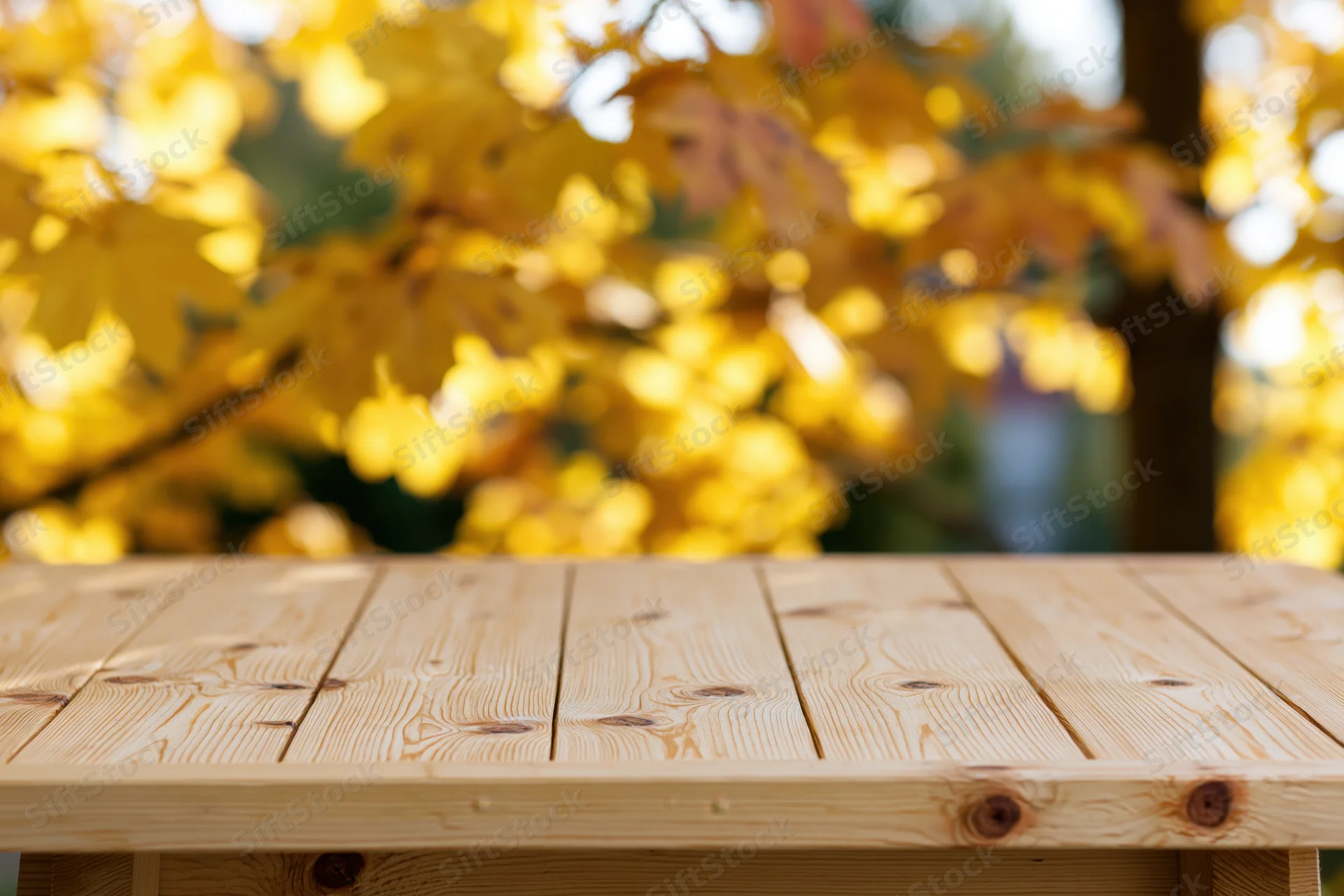 Light pine wooden table surface in foreground with blurred autumn foliage in background