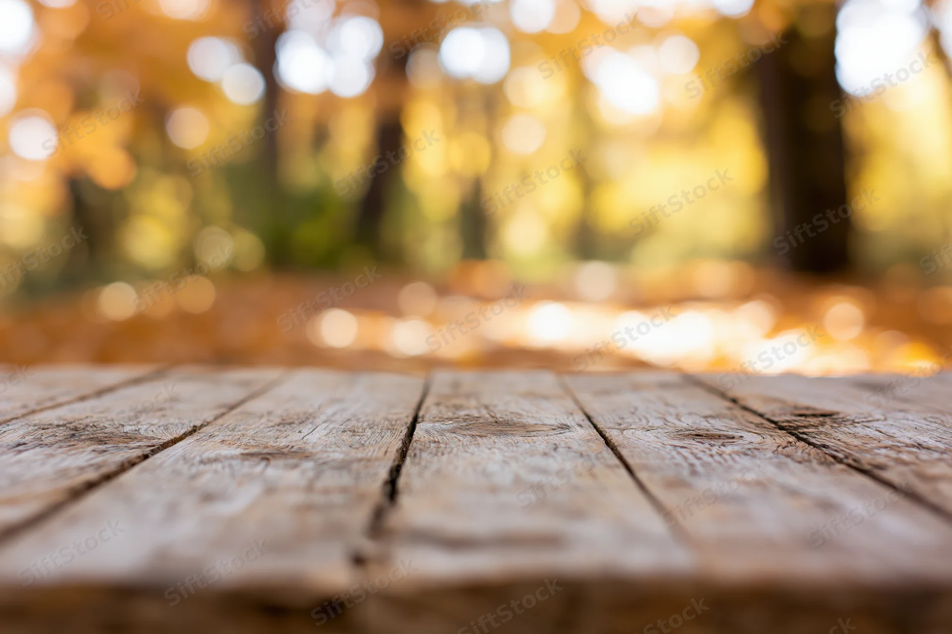 Rustic wooden table surface in a forest with autumn foliage and bokeh background