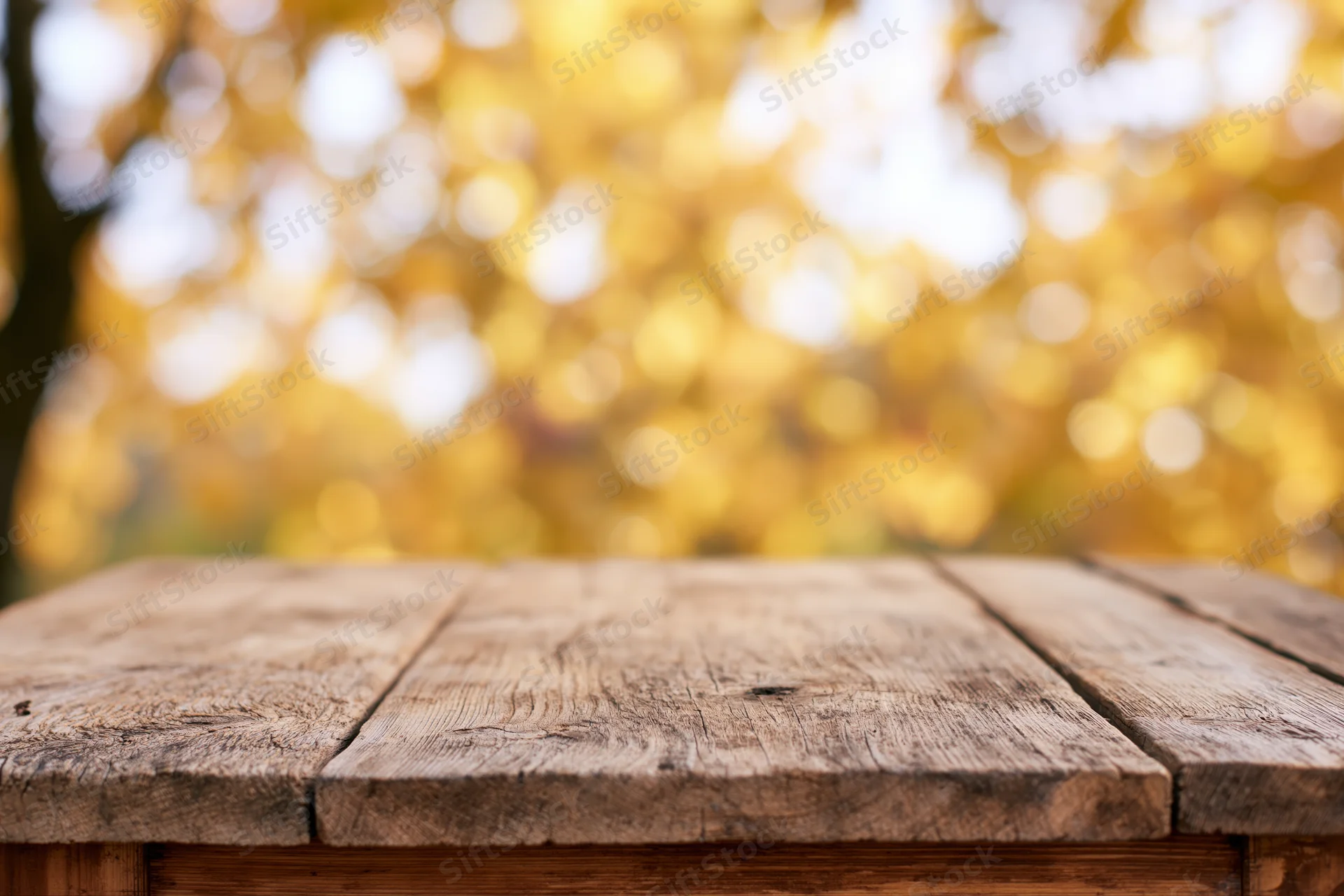 Rustic wooden table surface in foreground with blurred autumn foliage background