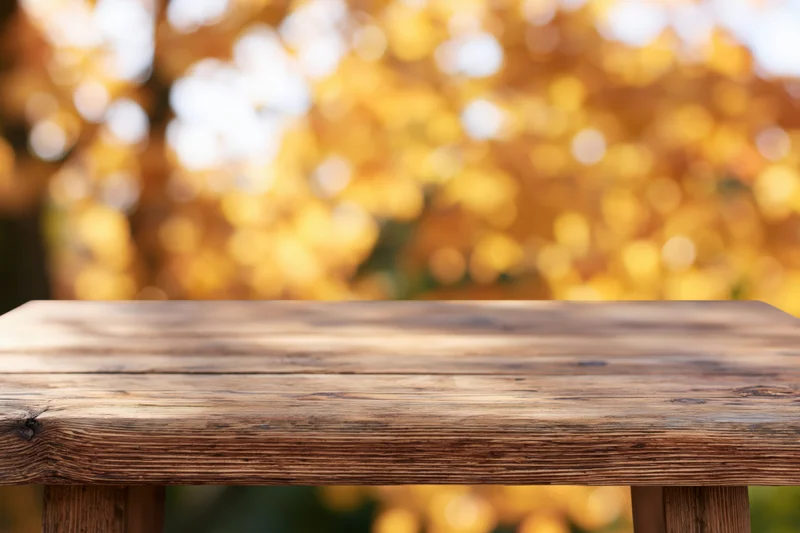Rustic wooden table surface in foreground with blurred autumn foliage background