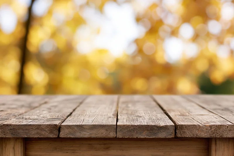 Rustic wooden table surface in an autumn outdoor setting with blurred yellow foliage background