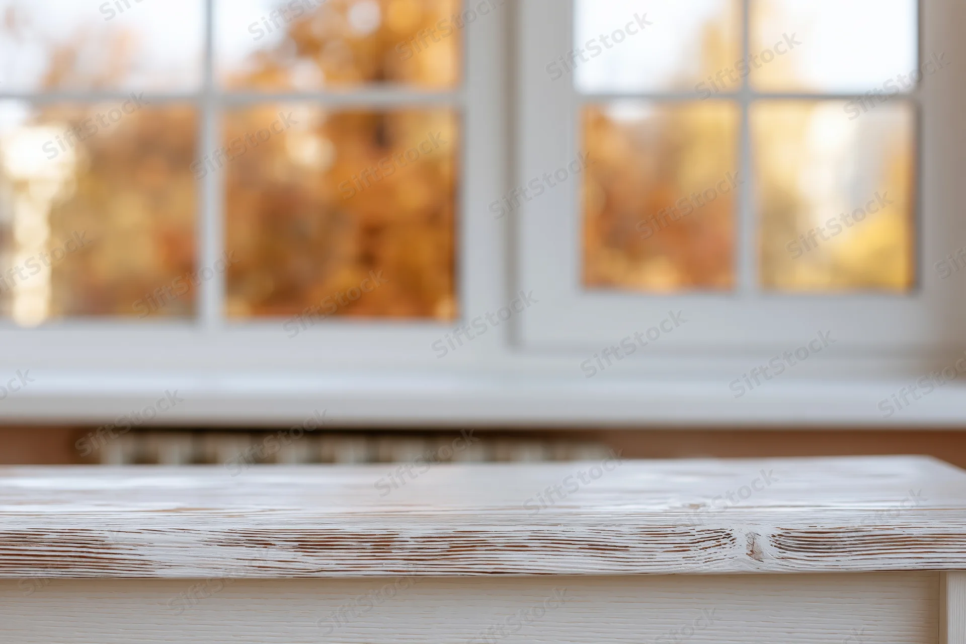 White-painted wooden table surface in sharp focus with blurred autumn window view in background
