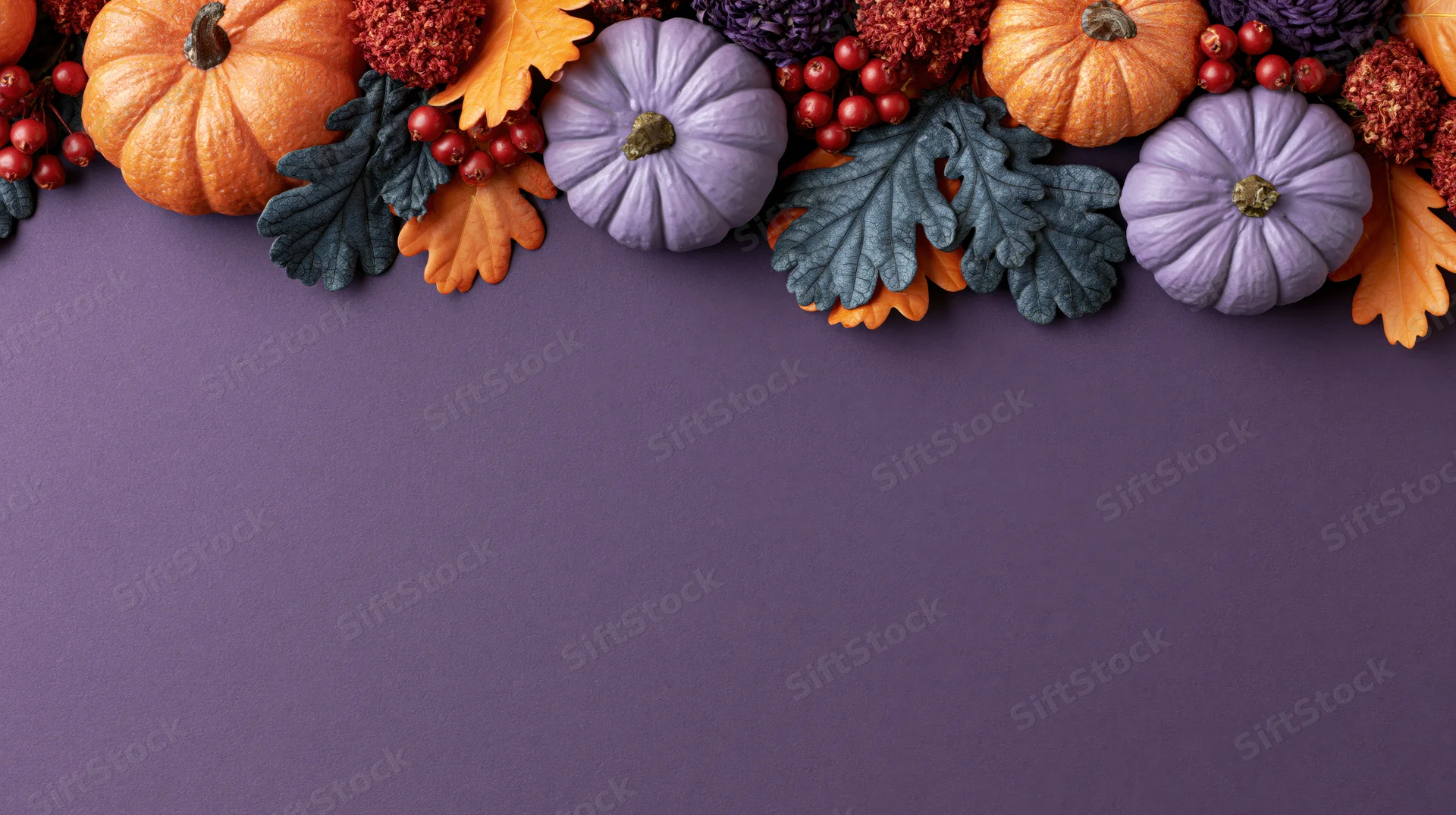 Autumn halloween decorations arranged along the top of a purple surface with copyspace below