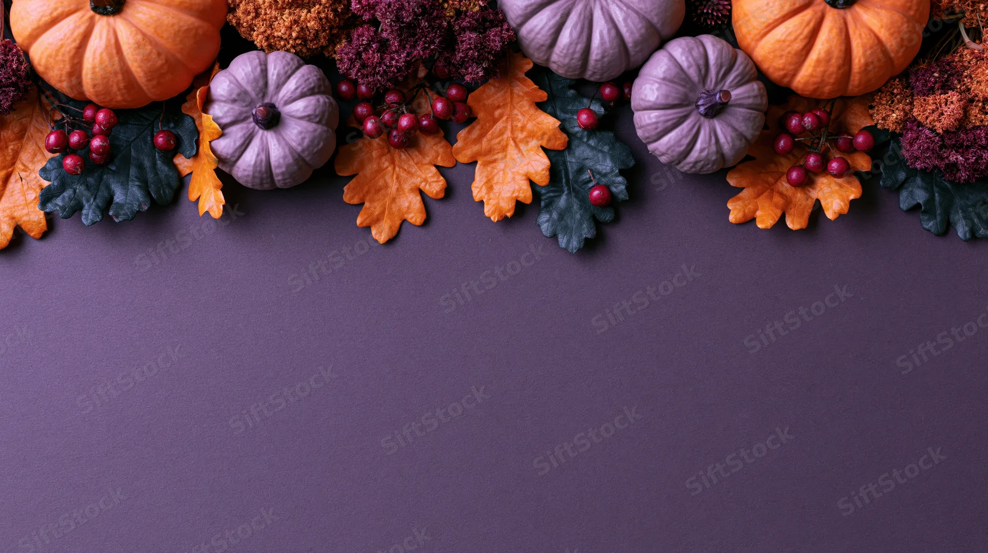 Autumn halloween decorations arranged along the top of a purple surface with copyspace below