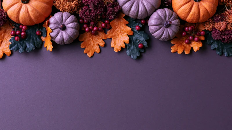 Autumn halloween decorations arranged along the top of a purple surface with copyspace below