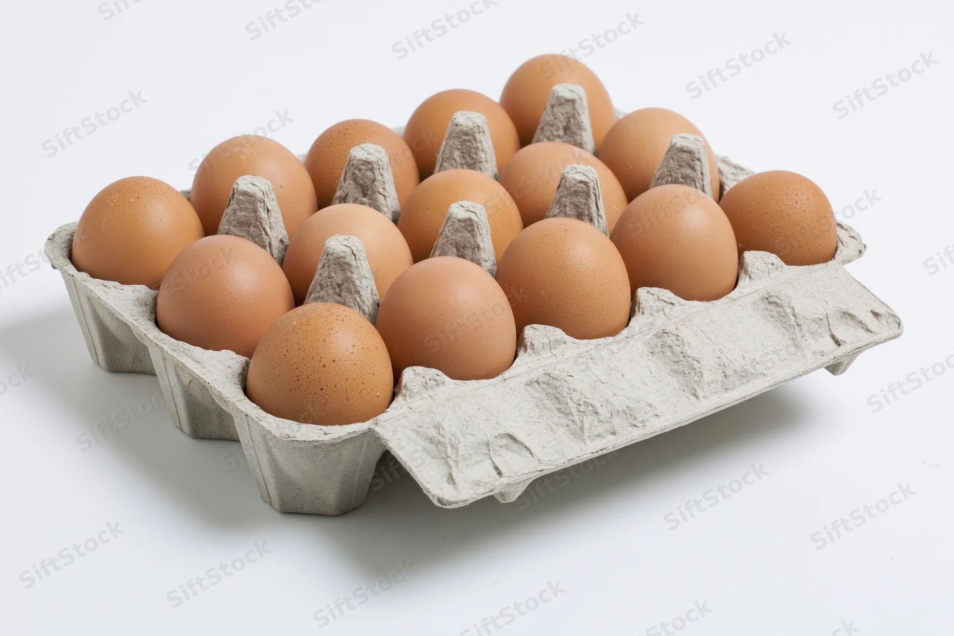 A dozen brown chicken eggs arranged in an open grey cardboard carton on a white surface