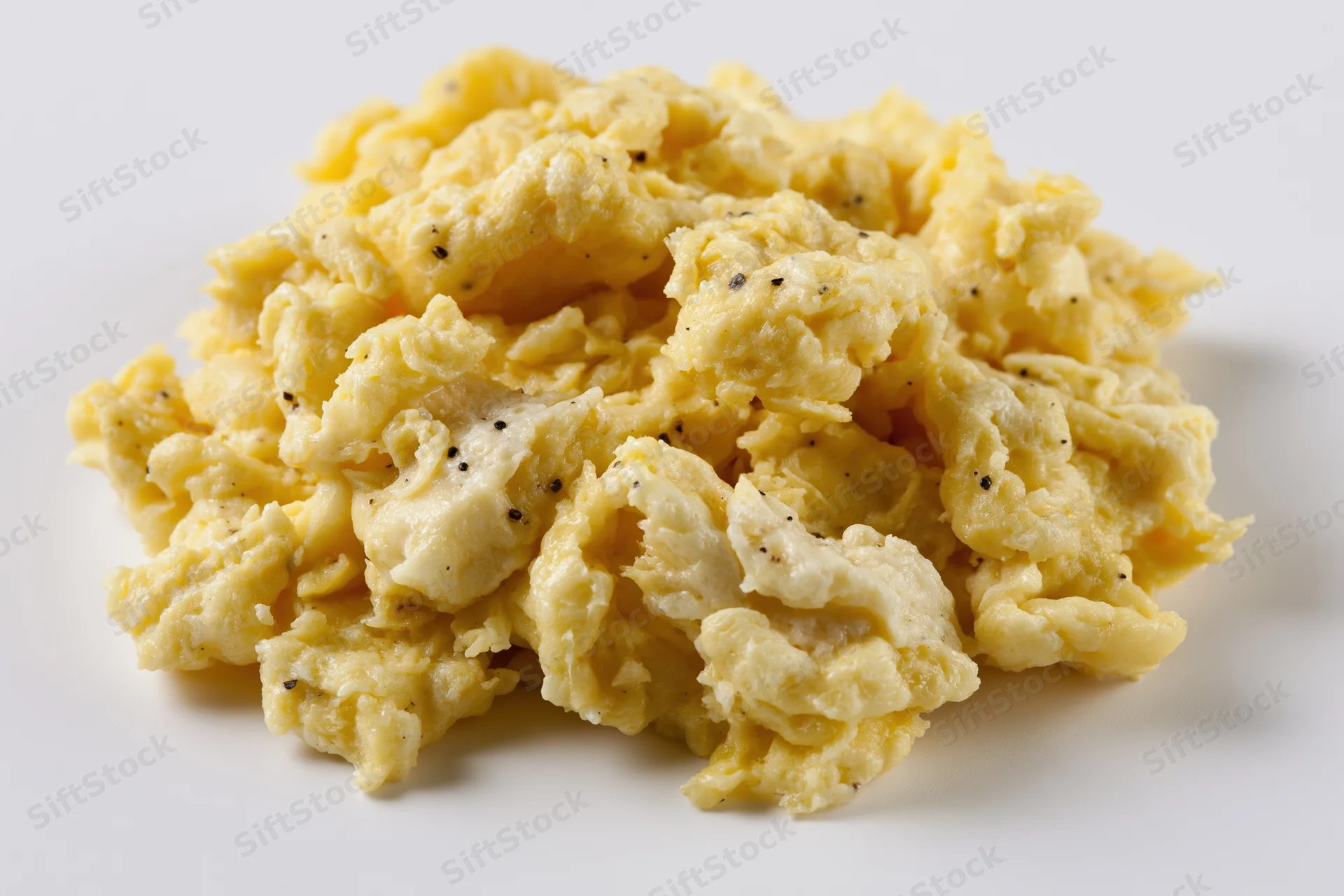 Pile of freshly cooked scrambled eggs on plain white surface