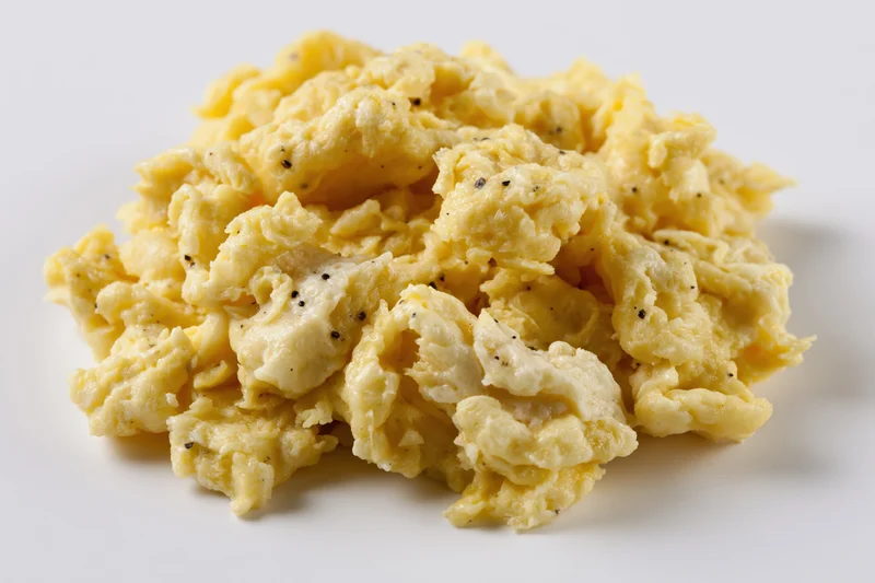 Pile of freshly cooked scrambled eggs on plain white surface