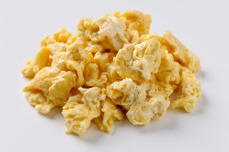 Pile of freshly cooked scrambled eggs on plain white surface