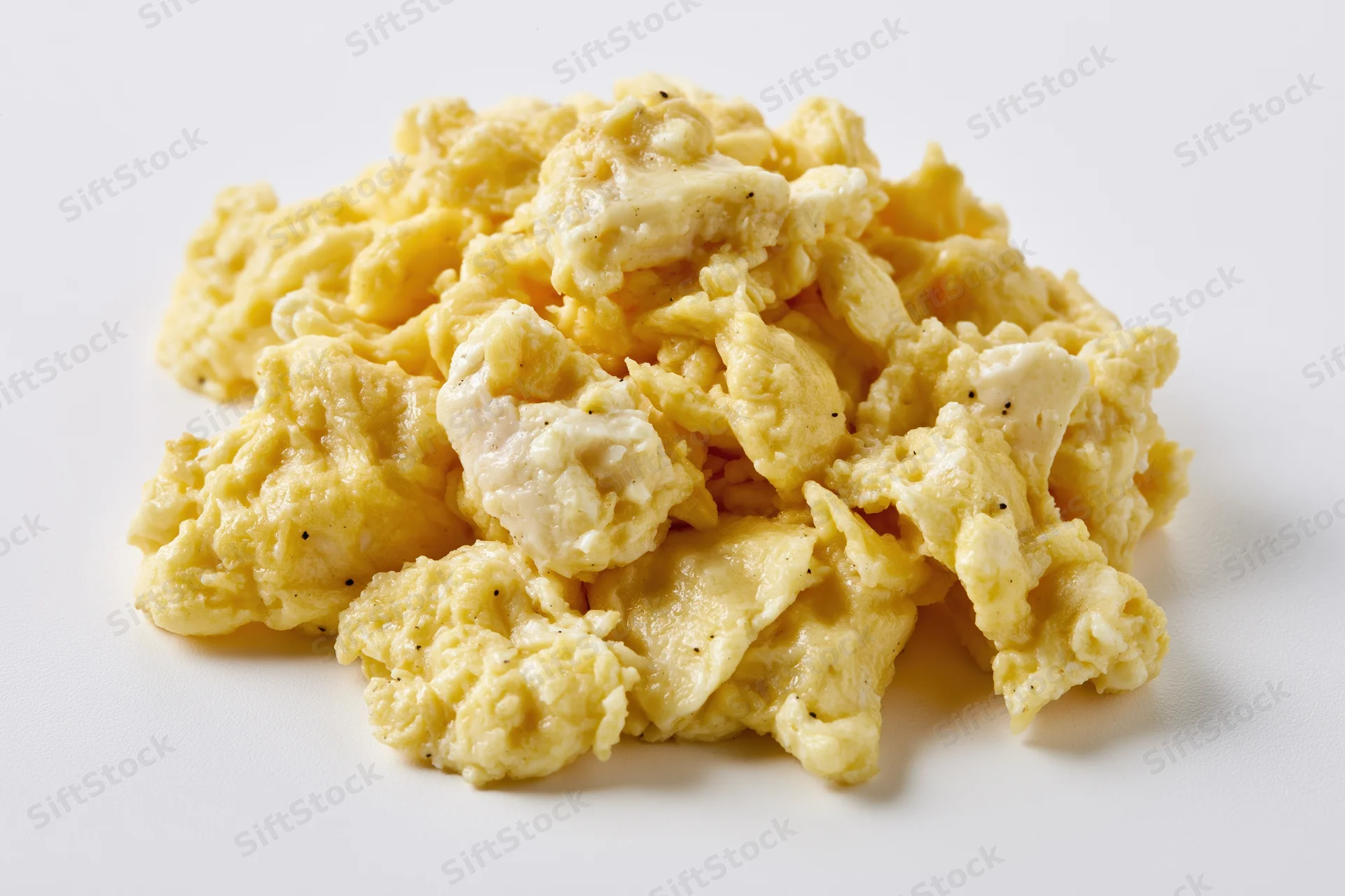 Pile of freshly cooked scrambled eggs on a plain white surface