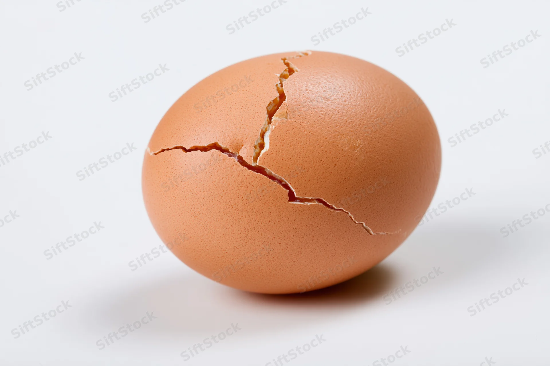 A single brown chicken egg with a jagged crack across its shell, isolated on white